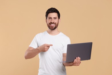 Happy man with laptop on beige background