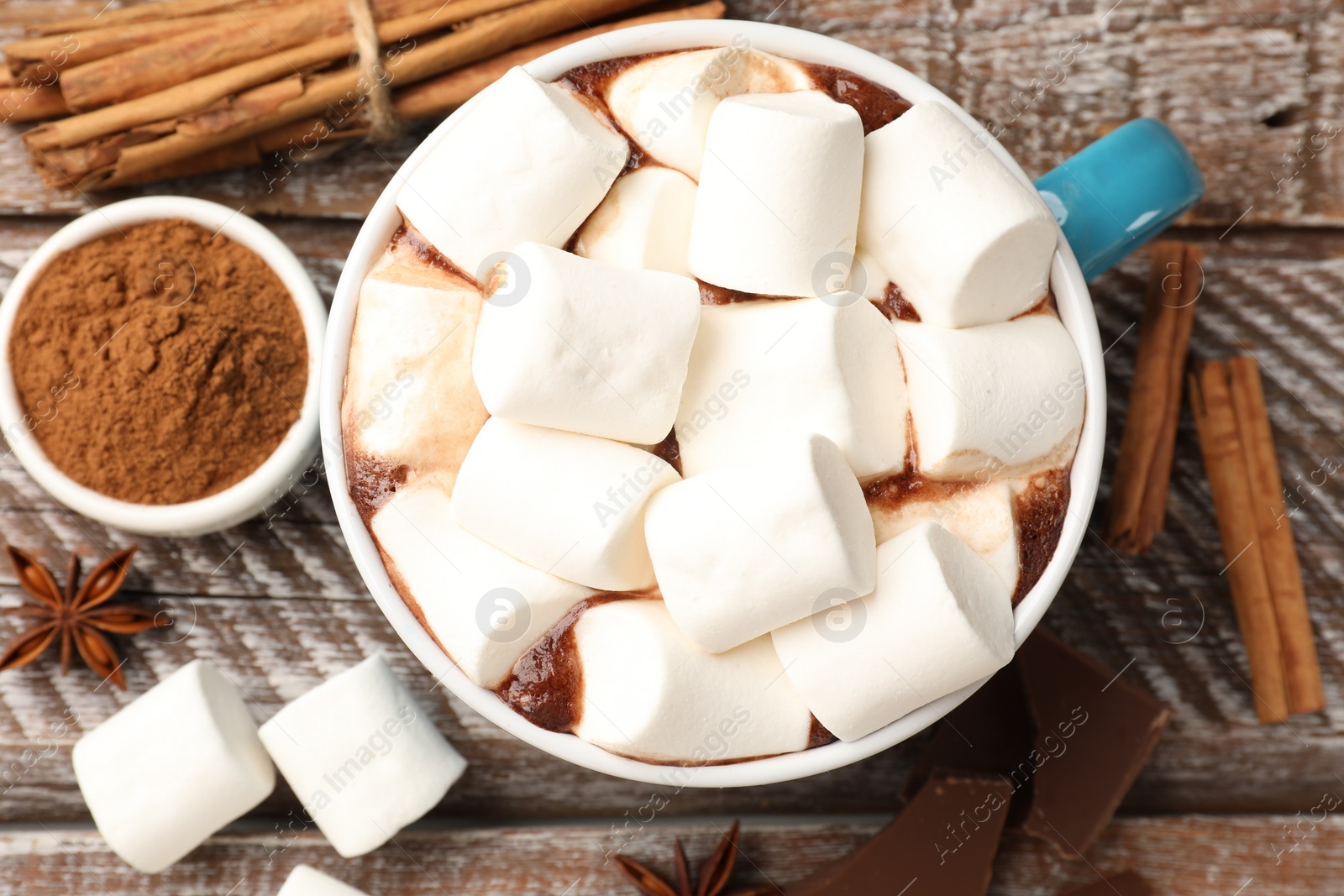 Photo of Tasty hot chocolate with marshmallows and ingredients on wooden table, flat lay