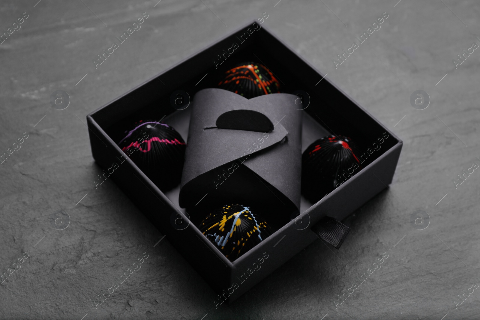 Photo of Box of tasty chocolate candies on black table