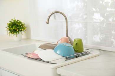 Photo of Drying rack with clean dishes over sink in kitchen