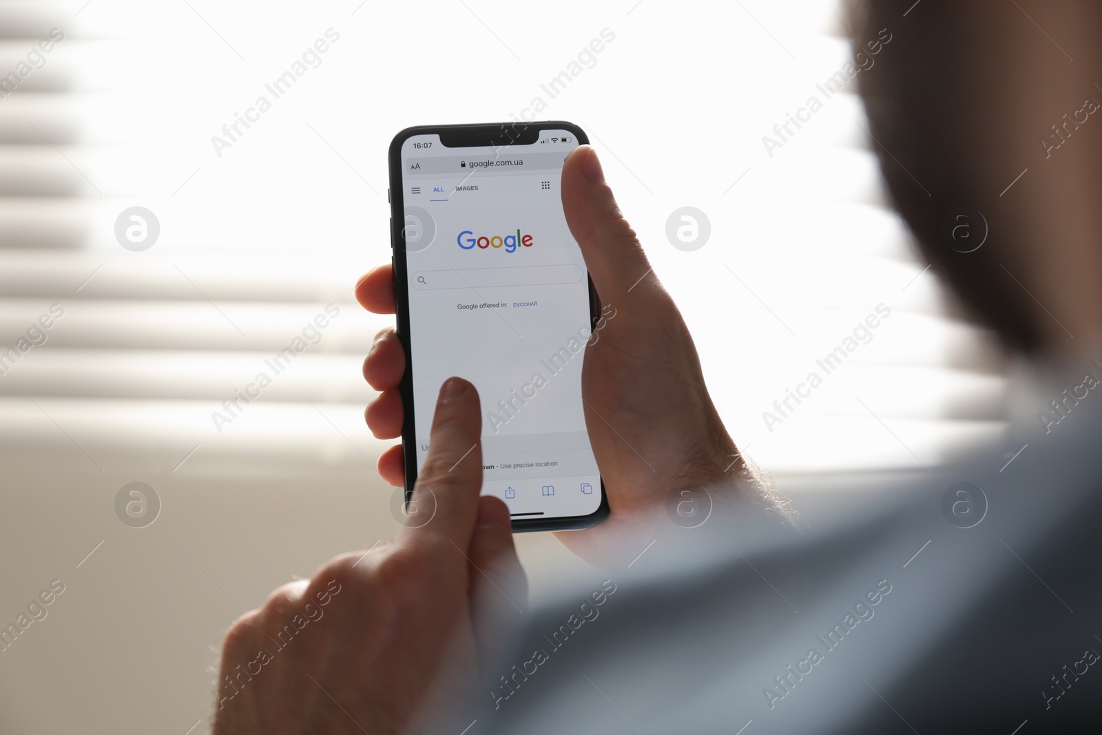 Photo of MYKOLAIV, UKRAINE - OCTOBER 27, 2020: Man using Google search engine on smartphone against blurred background, closeup