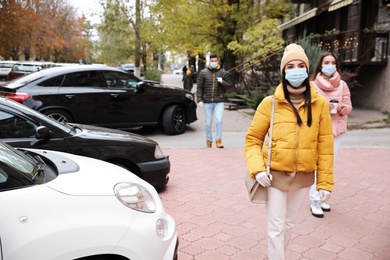 Young woman in medical face mask and gloves walking outdoors. Personal protection during COVID-19 pandemic