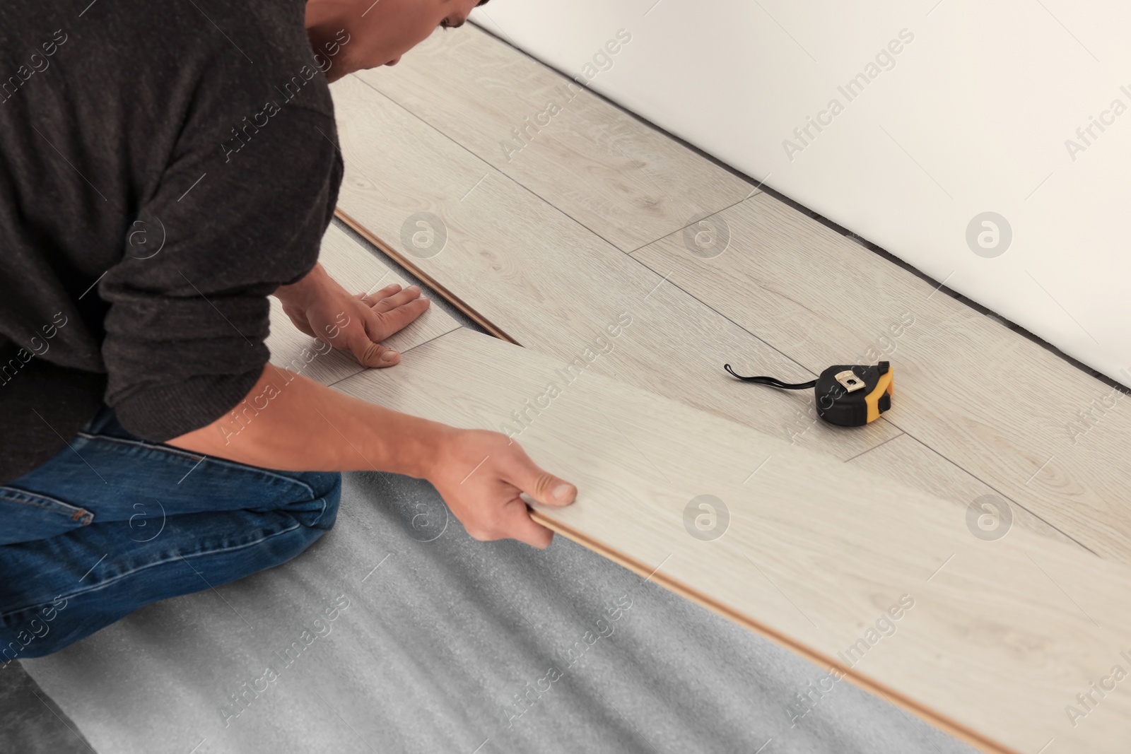 Photo of Professional worker installing new laminate flooring, closeup