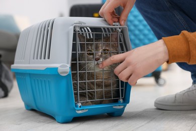 Photo of Travel with pet. Man closing carrier with cat indoors, closeup