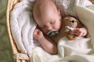 Cute newborn baby sleeping on white blanket in wicker crib, closeup