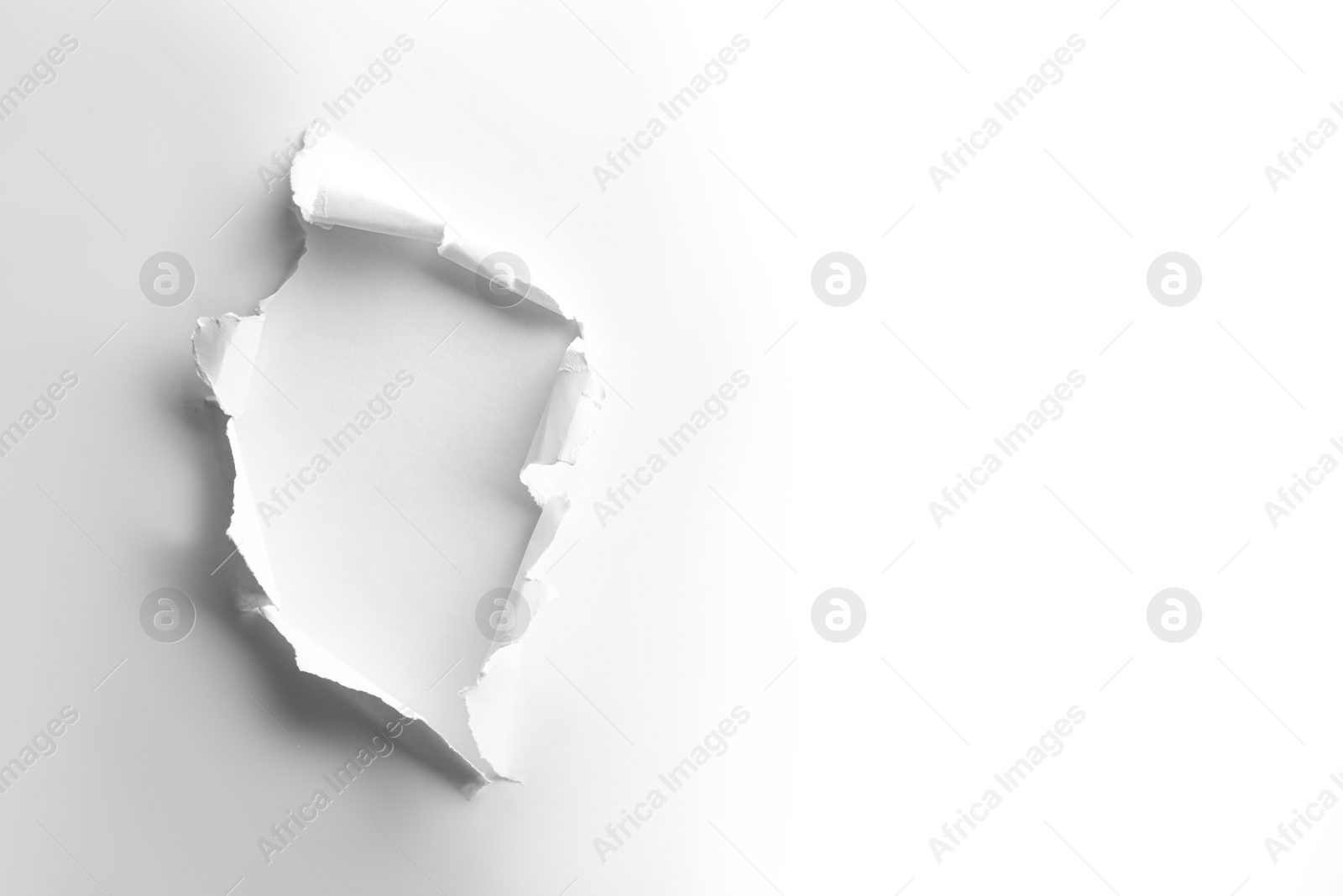 Photo of Hole in white paper on light background, space for text