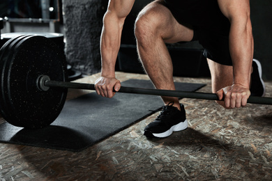 Photo of Man lifting barbell in modern gym, closeup