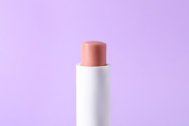 Photo of One lip balm on lilac background, closeup. Cosmetic product