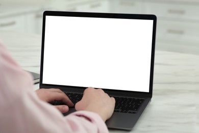 Woman using laptop at white table indoors, closeup