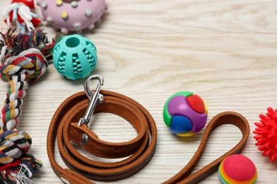 Photo of Brown leather dog leash and toys on white wooden background, closeup. Space for text