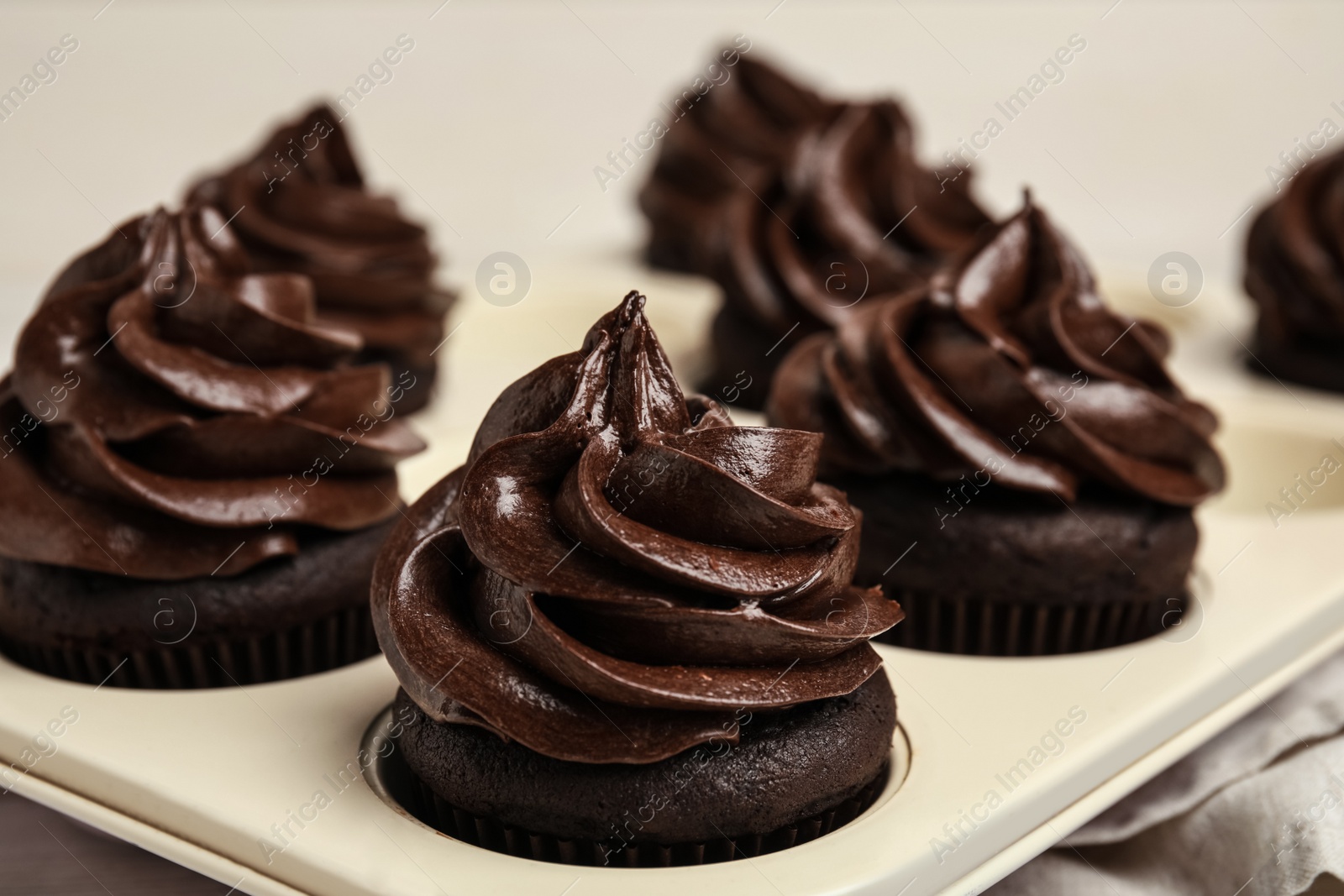 Photo of Delicious chocolate cupcakes with cream in baking tray, closeup