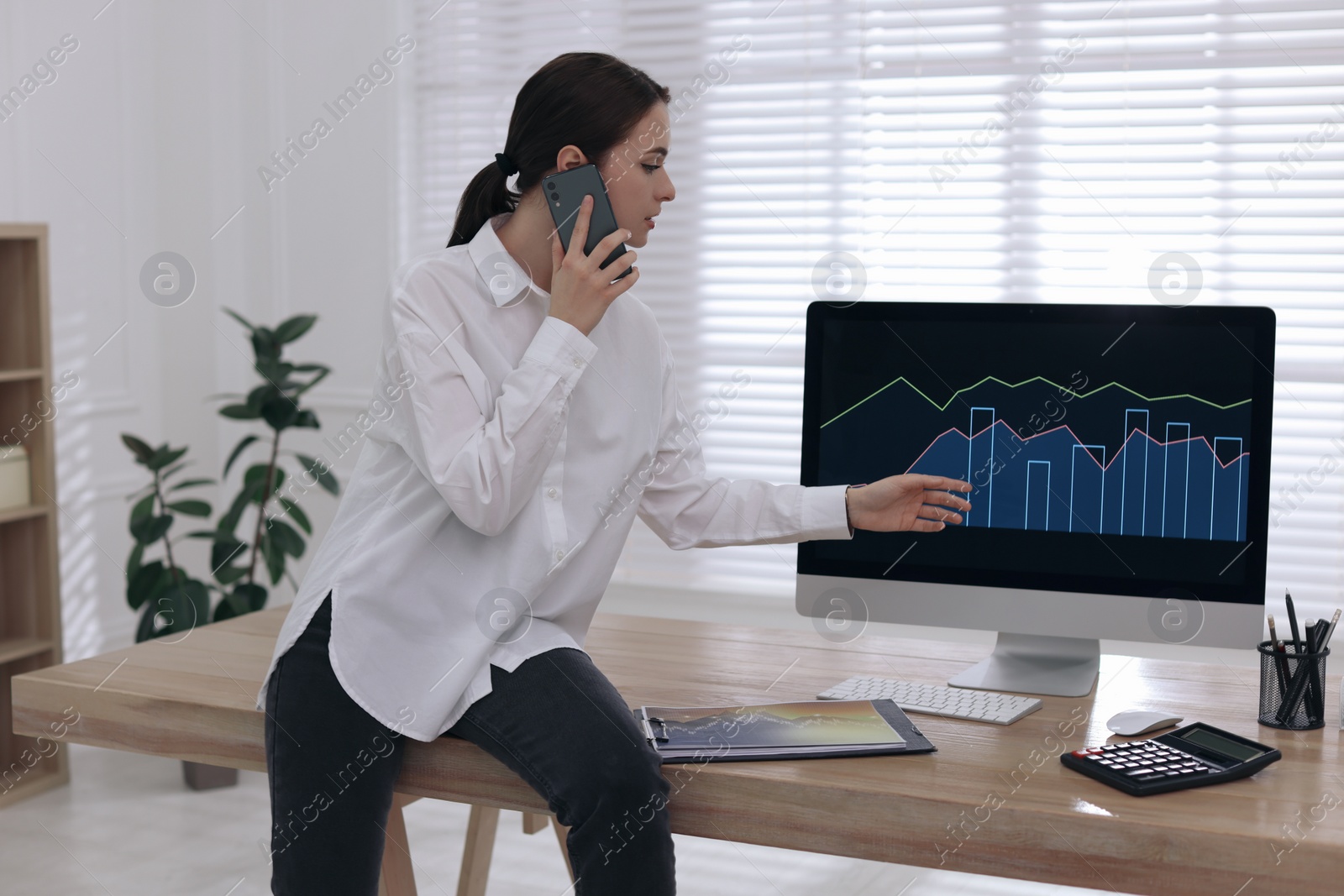 Photo of Businesswoman talking on phone while working in office. Forex trading