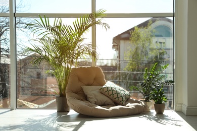 Cozy place with armchair pillow and potted plants at home