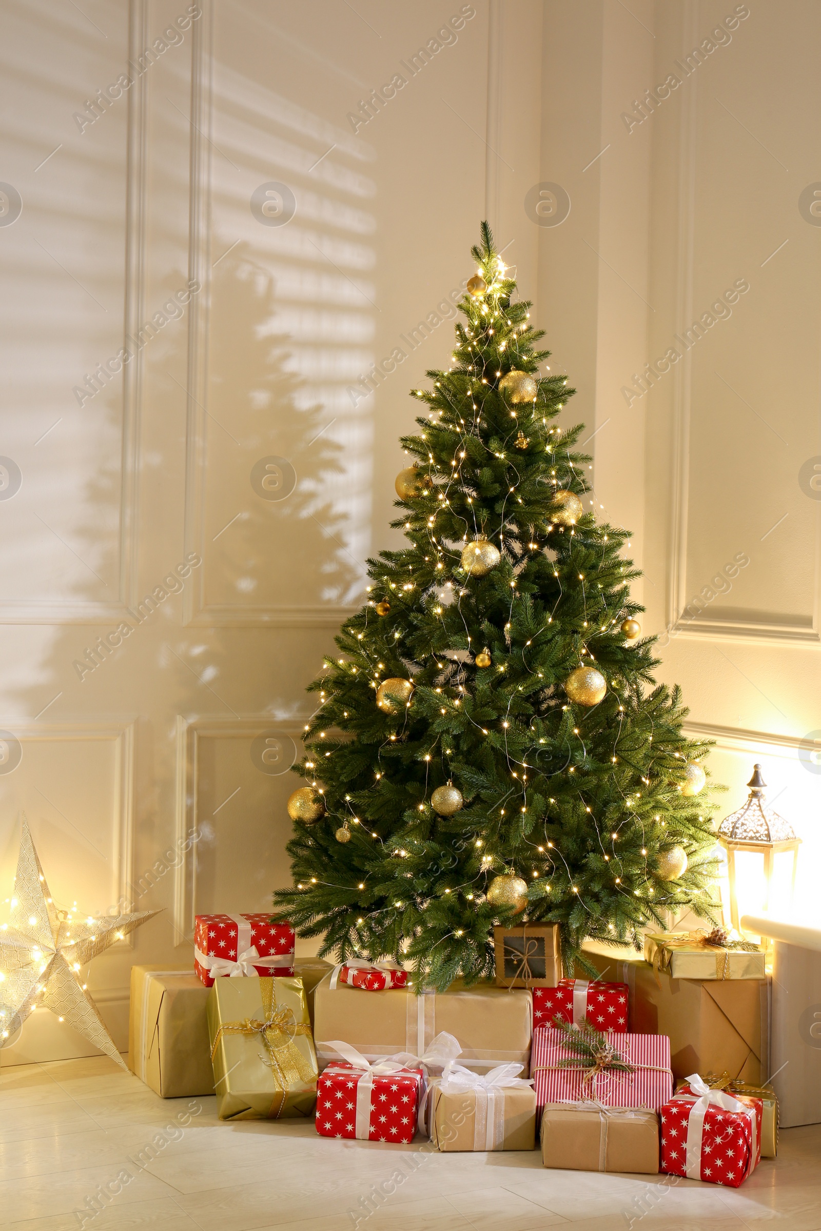 Photo of Gift boxes under Christmas tree with fairy lights indoors