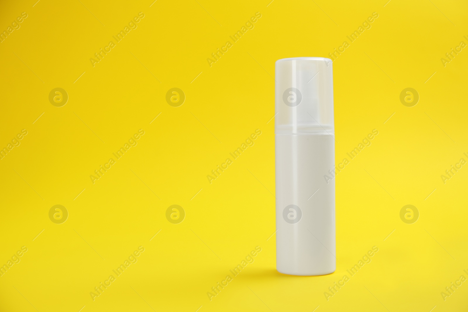 Photo of Bottle with insect repellent spray on yellow background, space for text