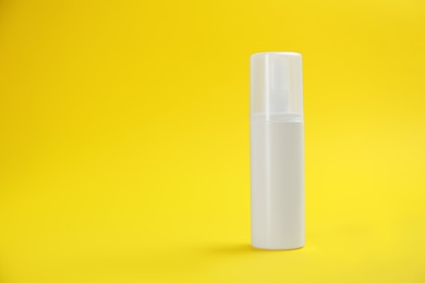 Photo of Bottle with insect repellent spray on yellow background, space for text