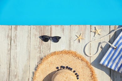 Photo of Beach accessories on wooden deck near outdoor swimming pool, flat lay