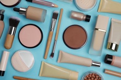 Photo of Face powders and other decorative cosmetic products on light blue background, flat lay