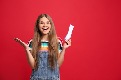 Portrait of happy young woman with lottery ticket on red background, space for text