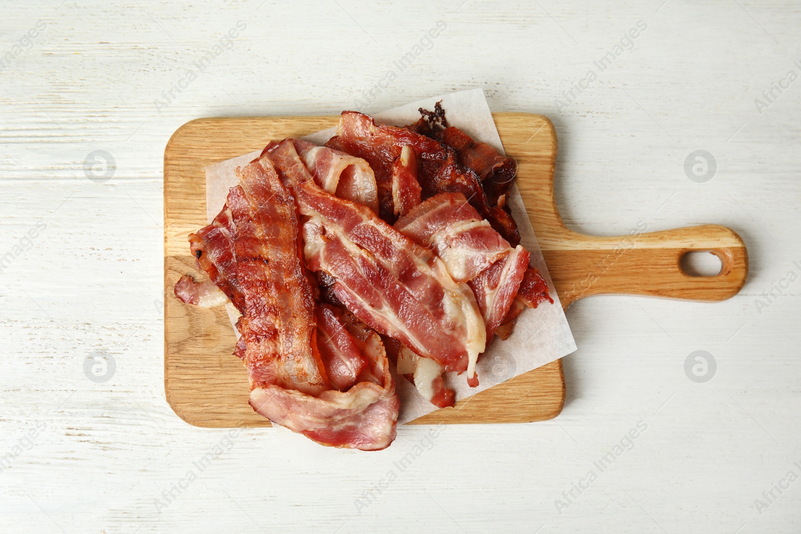 Photo of Slices of tasty fried bacon on white wooden table, top view