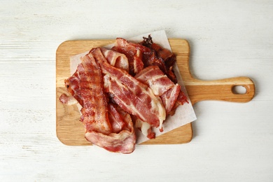 Slices of tasty fried bacon on white wooden table, top view