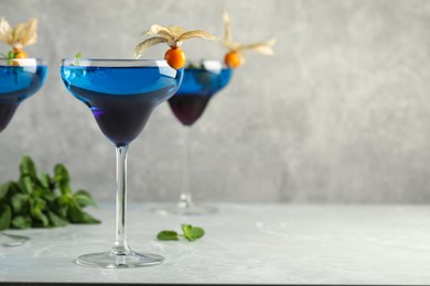 Photo of Tasty cocktail decorated with physalis fruits on grey table. Space for text