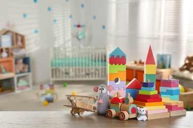 Image of Set of different cute toys on wooden table in children's room. Space for text
