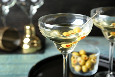 Photo of Glass of Classic Dry Martini with olives on wooden table, closeup