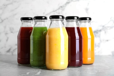 Bottles with delicious colorful juices on marble table