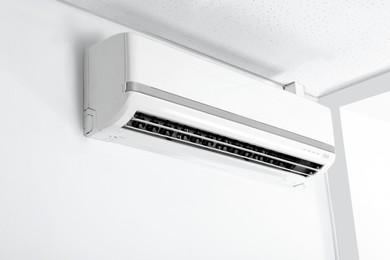 Photo of Modern air conditioner on white wall indoors