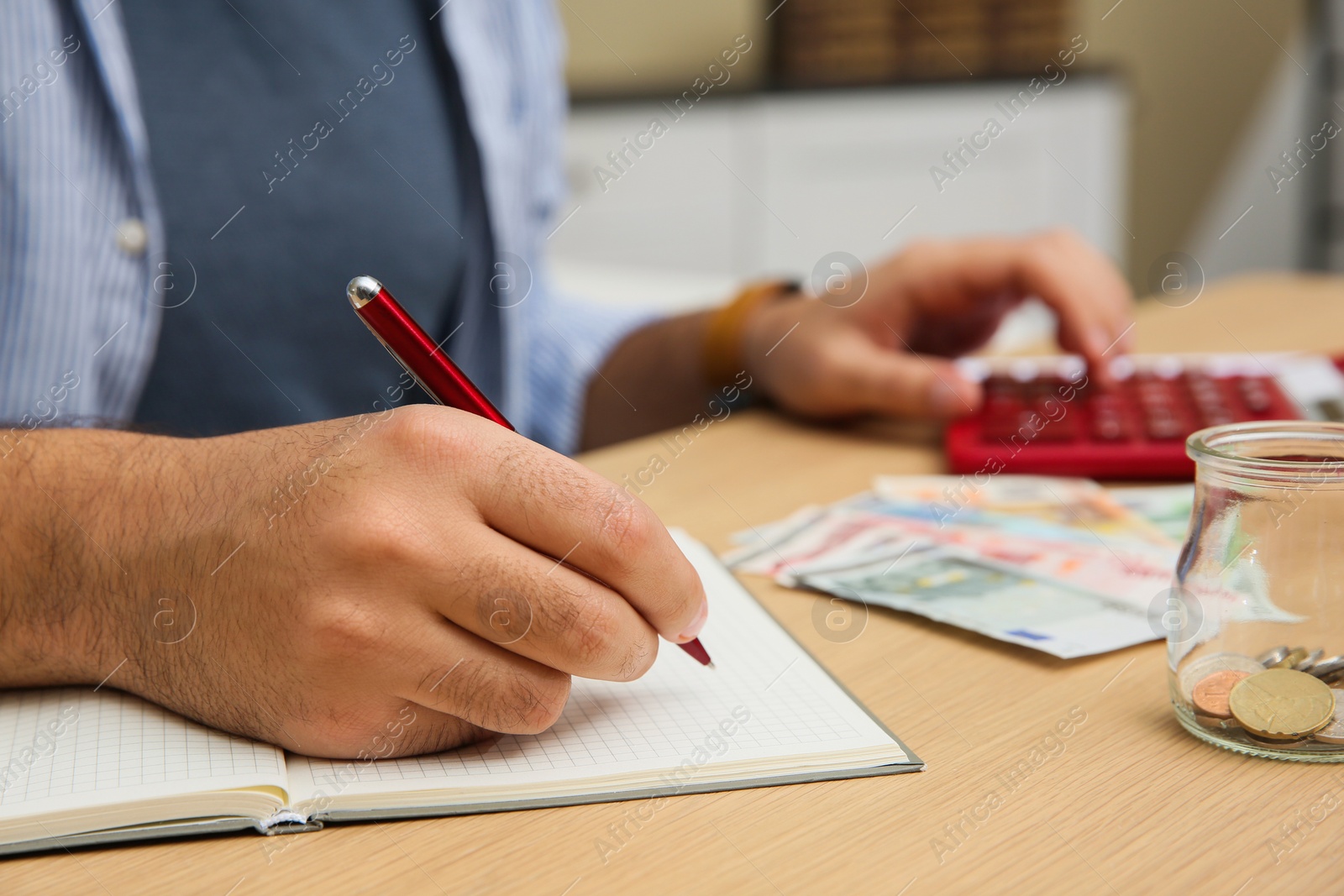 Photo of Man counting money with calculator at table indoors, closeup