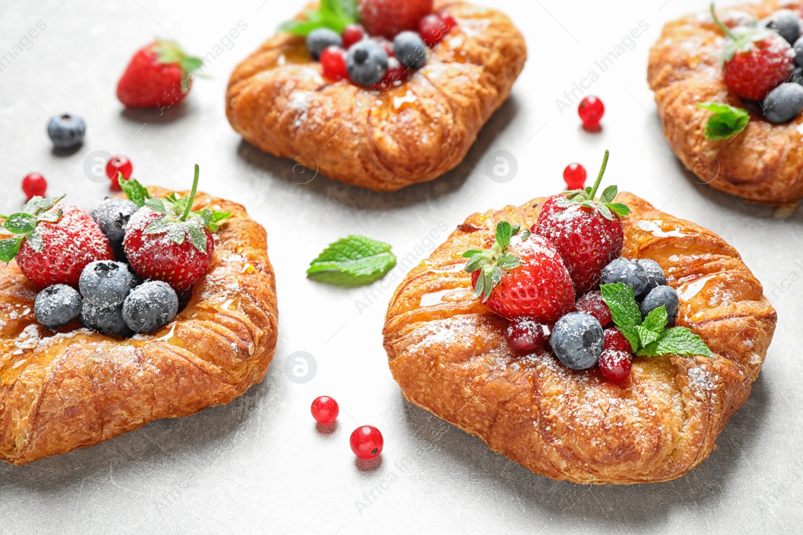 Photo of Fresh delicious puff pastry with sweet berries on light background