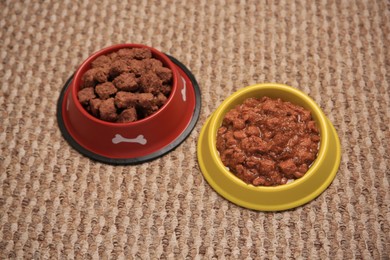 Wet pet food in feeding bowls on soft carpet, above view