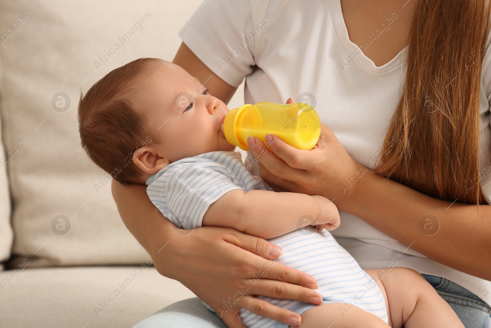 Photo of Mother feeding her cute child with infant formula indoors