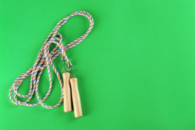 Photo of Skipping rope on green background, top view. Space for text
