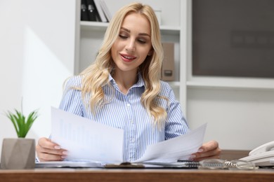 Secretary with documents at table in office