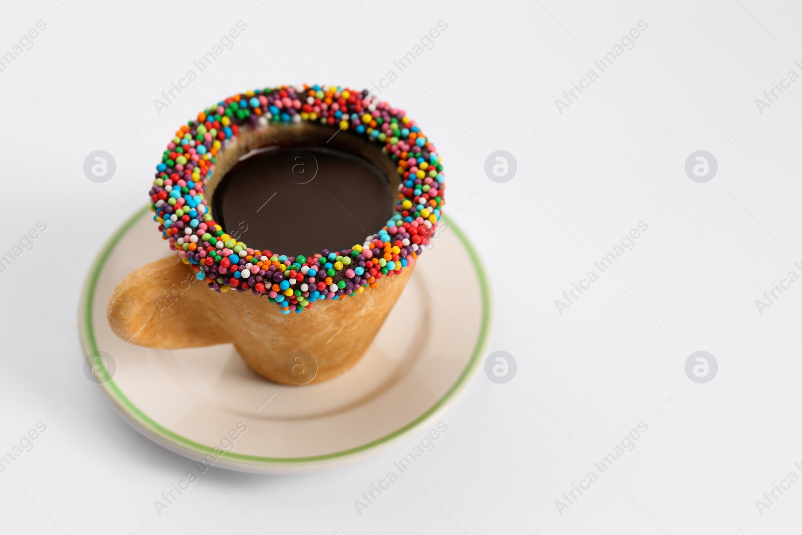 Photo of Delicious edible biscuit cup of coffee decorated with sprinkles on white background, space for text