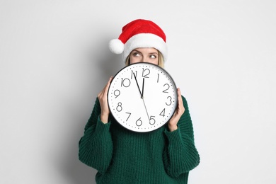 Photo of Woman in Santa hat with clock on white background. New Year countdown