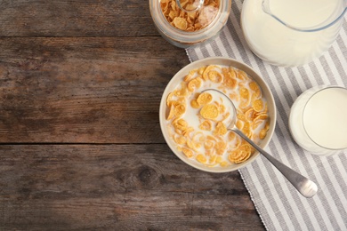Photo of Flat lay composition with healthy cornflakes and milk in bowl on wooden table. Space for text