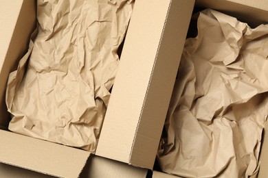 Photo of Open cardboard boxes with crumpled paper, top view. Packaging goods