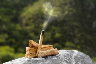 Burnt palo santo stick on stone surface outdoors