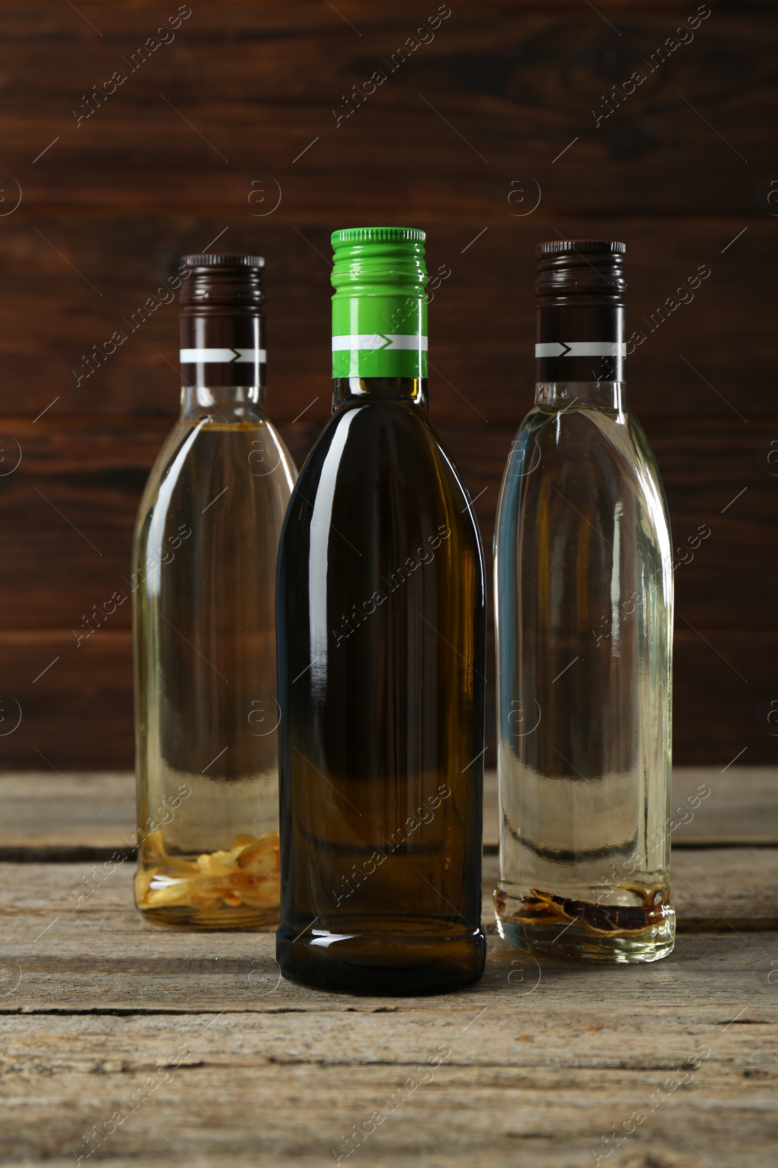Photo of Vegetable fats. Different cooking oils in glass bottles on wooden table
