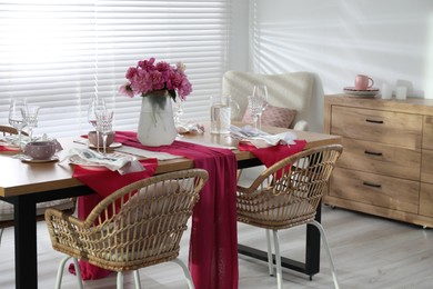 Photo of Pink peonies on table with beautiful setting and rattan chairs in dining room