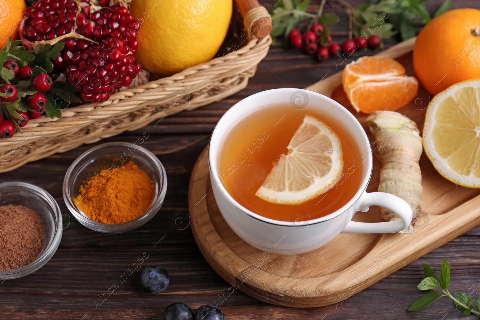 Photo of Cup of delicious immunity boosting tea and ingredients on wooden table