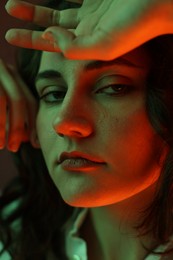 Portrait of beautiful young woman on color background with neon lights, closeup