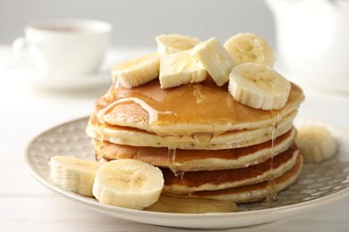 Photo of Delicious pancakes with bananas, honey and butter on white wooden table, closeup