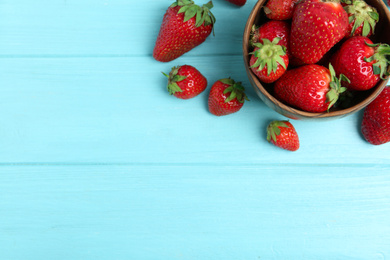 Photo of Delicious ripe strawberries in bowl on light blue wooden table, flat lay. Space for text