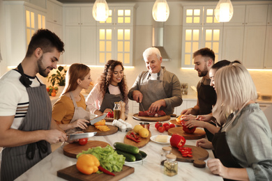 Happy people cooking food together in kitchen