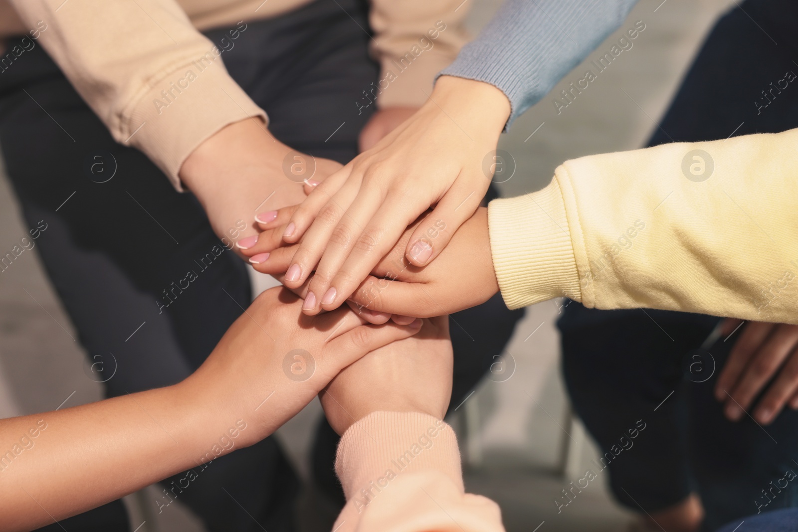 Photo of Group of people holding hands together indoors, closeup. Unity concept