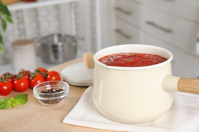 Fresh delicious tomato sauce on wooden table